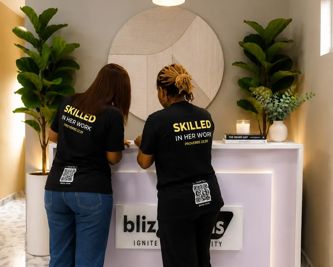 Two Blizsocials team members at the studio reception desk, in shirts reading Skilled In Her Work